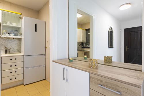 Modern kitchen and hallway in Marbella apartment with stainless steel appliances, wooden countertop, and access to bathroom