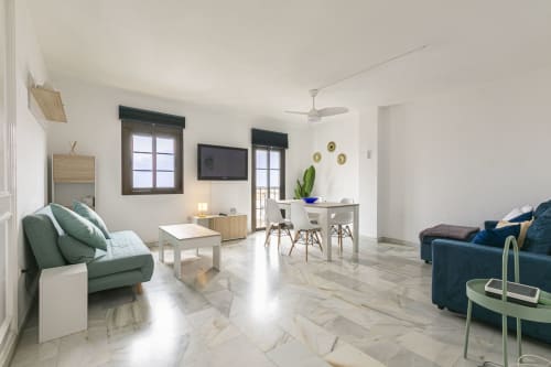 Modern Marbella apartment living room with marble floors, sea view, sofa seating, TV, and dining area