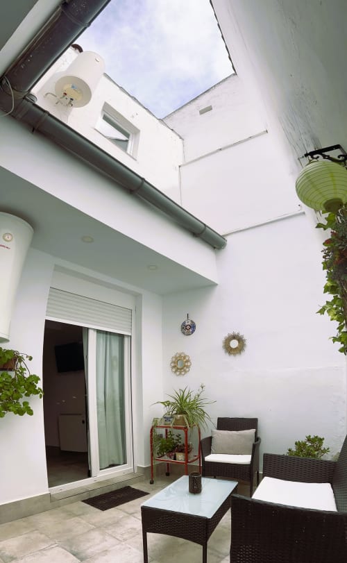 Patio moderno en departamento de Mérida con claraboya, cómodos asientos, plantas y paredes blancas