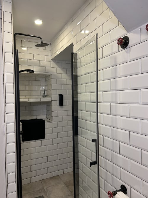 Moderno baño con azulejos blancos tipo metro y accesorios negros en apartamento de Mérida