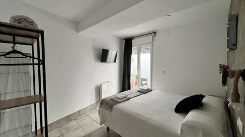 Moderno dormitorio en apartamento Gestyp-AT en Mérida con cama blanca, TV pantalla plana y acceso a balcón con vista a la ciudad