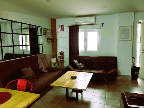 Sala de estar de apartamento moderno en Mérida con asientos de cuero marrón, mesa amarilla y paredes verde claro