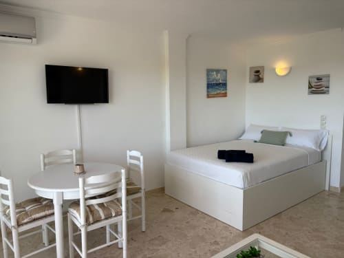 Apartamento moderno en SACORO Marbella con vistas al mar, cama, comedor, TV y decoración costera