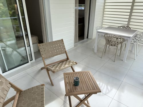 Terrasse moderne du Domaine de la Glacière avec chaises en bois, table blanche et transats surplombant Petit Bourg