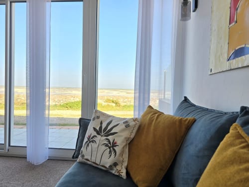 Bright living room at Gîte La mer cottage in Saint-Marcouf with large windows overlooking sea view, comfortable sofa with