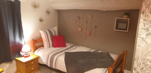 Chambre douillette à La Maison de Philomène B&B à Corme-Royal avec literie rayée, oreiller rouge, mobilier en bois et jardin