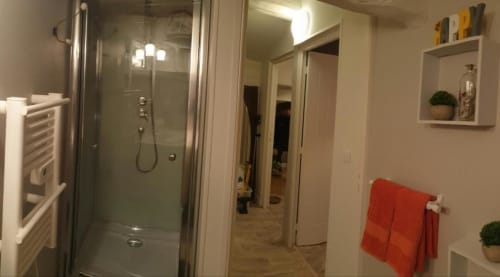 Salle de bain moderne à La Maison de Philomène B&B à Corme-Royal avec douche vitrée, serviettes rouges et sanitaires blancs