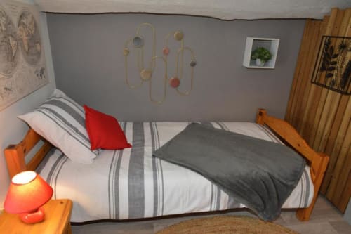 Chambre Capucine à La Maison de Philomène B&B, Corme-Royal : lit en bois avec literie rayée, décoration rouge