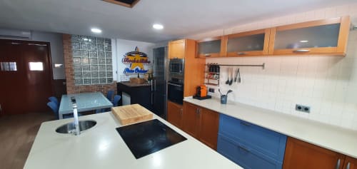 Cocina moderna en Villa Castelló Salou con muebles naranjas, encimeras blancas, zona de comedor y toques azules