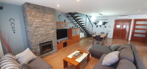 Sala moderna en Villa Castelló Salou con chimenea de piedra, muebles naranjas, suelo de madera y mapa mural