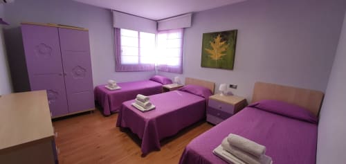 Habitación triple con temática púrpura en Villa Castelló Salou, tres camas, suelos de madera y equipamiento moderno