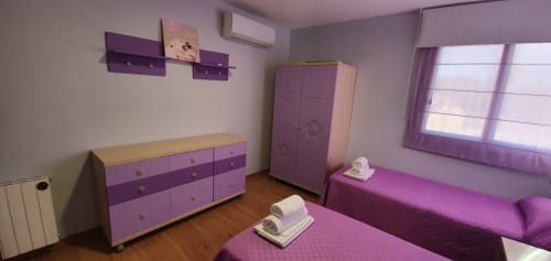 Dormitorio con tema púrpura en Villa Castelló Salou con dos camas, cómoda de madera y armario en Salou