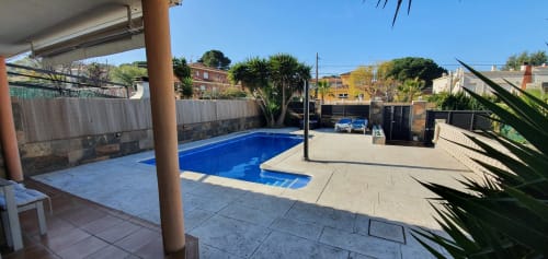 Zona de piscina de Villa Castelló Salou con piscina azul, terraza, palmeras y ambiente mediterráneo soleado