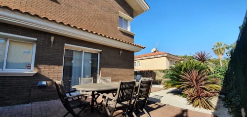 Patio de Villa Castelló Salou con mesa de comedor y sillas con vistas al jardín mediterráneo