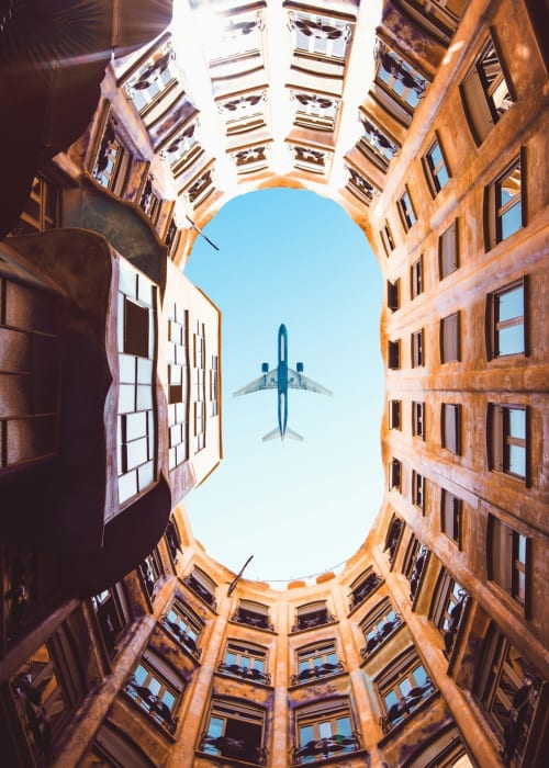Avión volando sobre el patio de un edificio residencial en Salou, visto desde abajo contra un cielo azul despejado