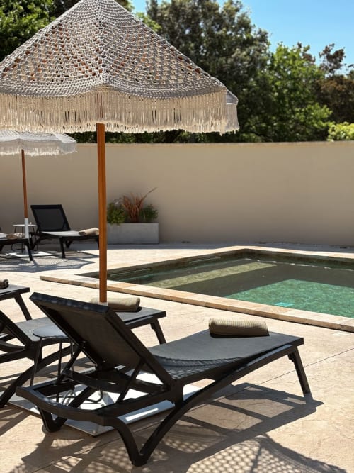 Espace piscine de villa de luxe avec parasol macramé beige, chaises longues et piscine chauffée à La Maison D'ambrine à Chamaret