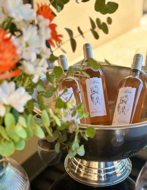 Bottiglie di rosato che si raffreddano in un secchiello di metallo circondato da fiori bianchi e arancioni a La Maison D'ambrine, Chamaret