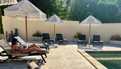 Donna che si rilassa su una sdraio sulla terrazza della piscina di La Maison D'ambrine a Chamaret, Francia con ombrelloni e area relax