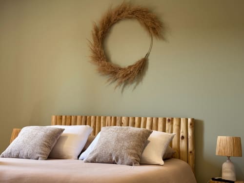 Camera rustica con testata in legno, corona decorativa di erba della pampa e cuscini stratificati presso La Maison D'ambrine B&B