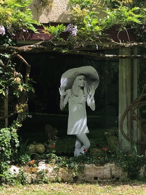 White statue of woman in wide-brimmed hat among flowering vines at Domaine de l'Ocrerie, Pourrain