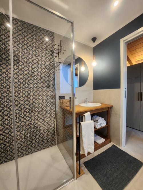 Modern bathroom at Locanda del Sasso Rooms in Crodo with walk-in shower, wooden vanity, and round mirror