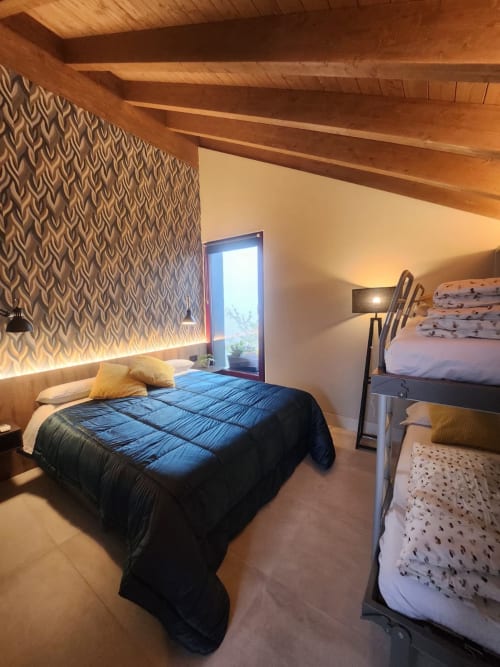 Cozy bedroom at Locanda del Sasso with exposed beams, geometric wallpaper, and mountain views from Crodo