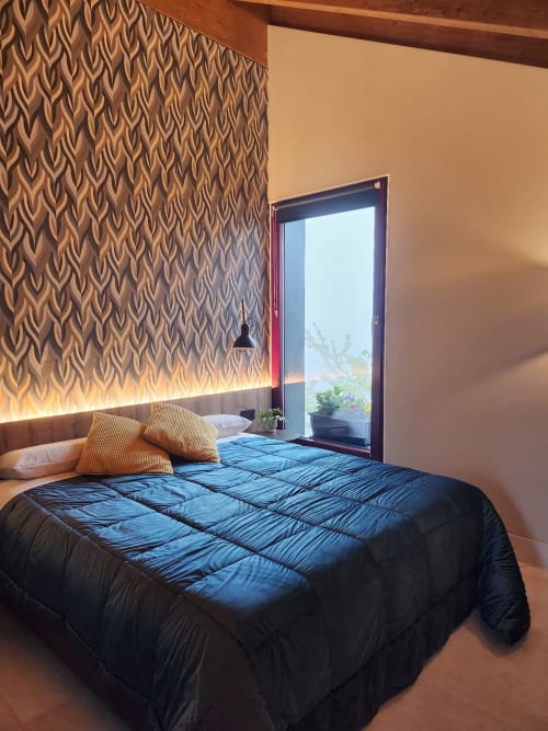 Modern bedroom at Locanda del Sasso Rooms in Crodo with blue comforter, patterned headboard, and mountain view through glass