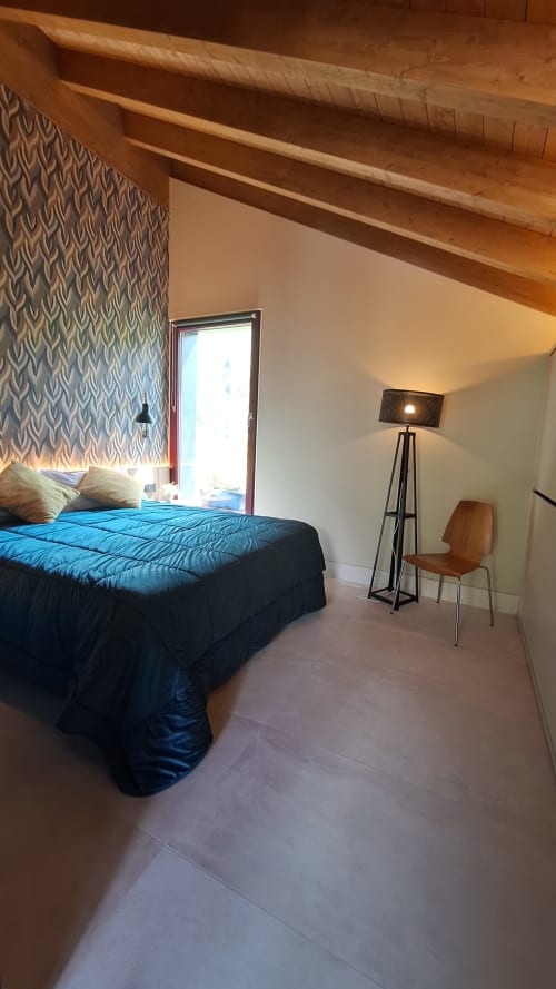 Modern bedroom at Locanda del Sasso Rooms in Crodo with blue bedding, wooden beams, and mountain view door