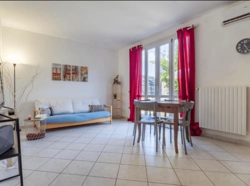 Bright studio apartment in Ferrara with sofa bed, dining table, and red curtains overlooking windows