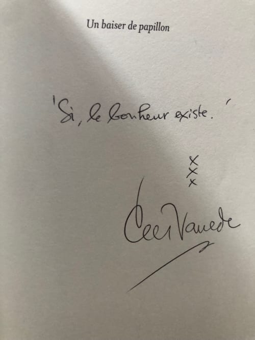 Handwritten French note on white paper: 'Un baiser de papillon' with 'Si, le bonheur existe' and signature at Domaine de
