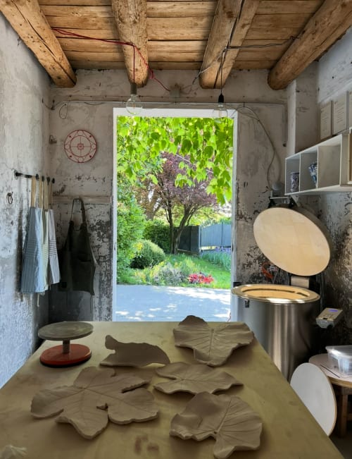 Rustic pottery studio at La Cascina di Bea B&B in Bergamo, Italy, with clay leaf sculptures and garden view