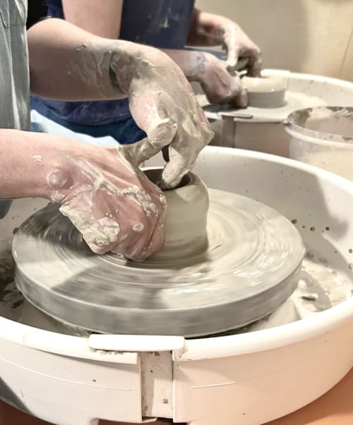 Guest hands shaping clay on pottery wheel at La Cascina di Bea, Torre Boldone