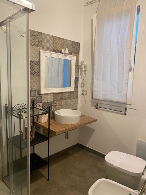 Moderno bagno di Corte Sicula B&B a Siracusa con lavabo a bacinella, specchio bianco e doccia walk-in