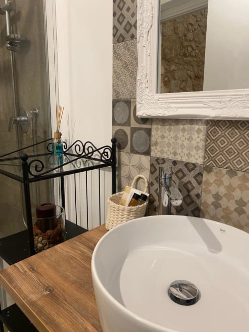 Bagno moderno a Corte sicula BnB a Siracusa con lavabo rotondo bianco, piastrelle decorative e specchio ornato