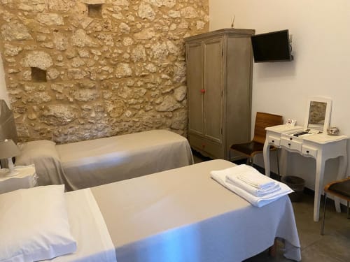 Camera accogliente a Corte Sicula B&B a Siracusa con muri in pietra, biancheria bianca e arredi rustici
