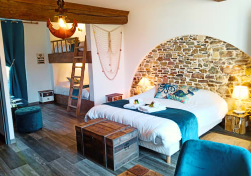 Chambre familiale à thème maritime avec lit double et lit superposé, mur en pierre apparente et ambiance chaleureuse en Normandie.