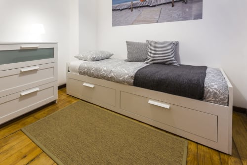 Quarto moderno em A Lodge in Blue, Aveiro com cama estofada creme, roupa de cama estampada e piso de madeira