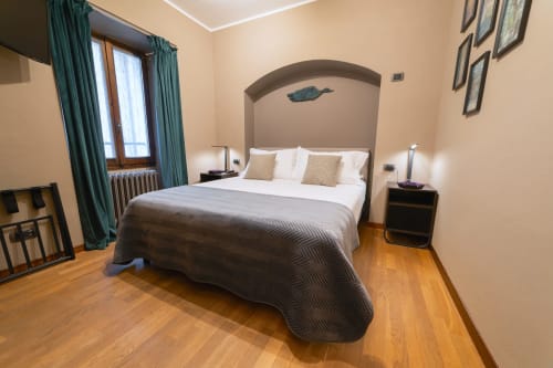Spaziosa camera da letto nell'appartamento La Risorgente a Varenna by Foot con testata ad arco, biancheria bianca, pavimenti in legno e turchese