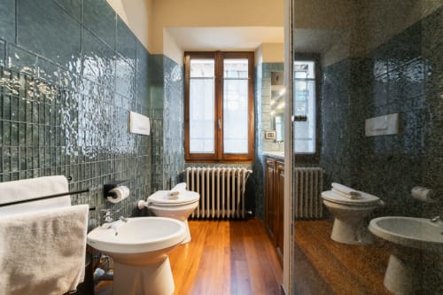 Lussuoso bagno dell'appartamento La Risorgente a Varenna con doppio lavabo, piastrelle turchesi, pavimento in legno