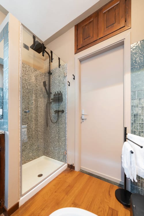 Bagno moderno con doccia a filo pavimento, pavimento in legno e portasciugamani bianco presso l'appartamento hotel Varenna by Foot