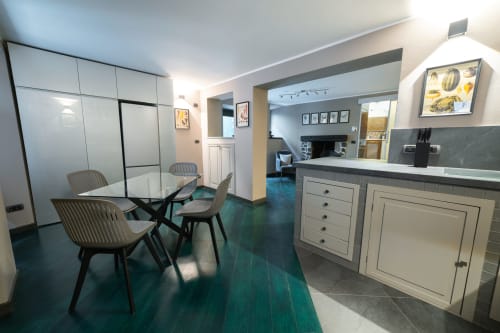 Zona living moderna nell'appartamento La Risorgente dell'hotel Varenna con tavolo in vetro, sedie e bancone cucina