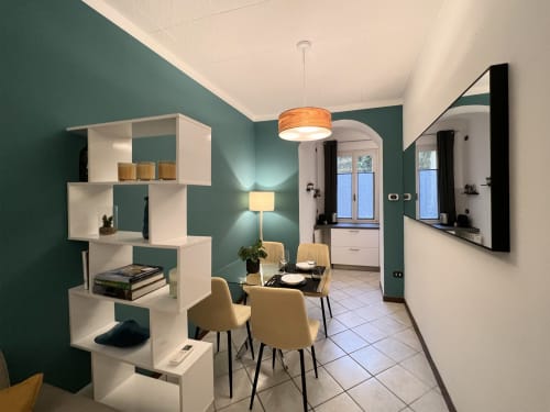 Modern apartment dining area at Varenna by Foot with teal walls, white shelving, wooden chairs, pendant light, and access to