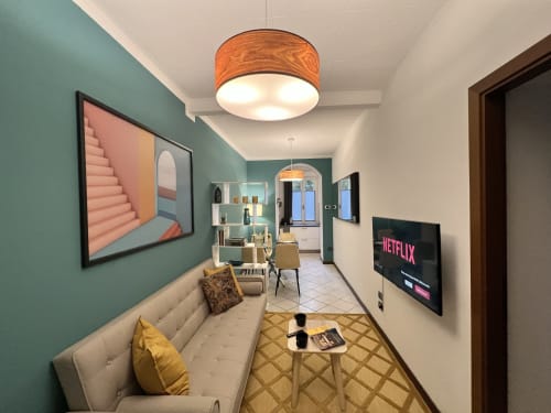 Modern apartment living room in Varenna with teal accent walls, cream sofa, wood ceiling light, wall-mounted TV, and