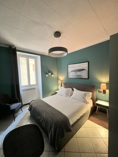 Modern bedroom at Varenna by Foot with teal walls, queen bed, pendant lighting, and garden view door