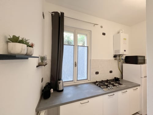 Modern kitchen in Varenna apartment with white cabinets, gas cooktop, and garden view doors
