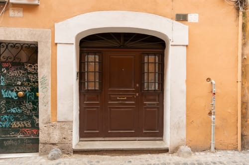 Brown wooden door with white archway on orange terracotta building in Roma Trastevere, Casa Verde luxury apartment entrance