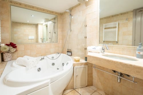 Luxury bathroom with Jacuzzi tub, double sink, walk-in shower, and heated towel rack in Casa Verde apartment, Rome