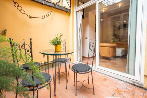 Cozy balcony seating area at Casa Verde luxury apartment in Rome Trastevere with wrought iron furniture and yellow walls