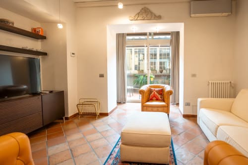 Luxury Trastevere apartment living room with orange leather chairs, terracotta flooring, and balcony views, Casa Verde Roma