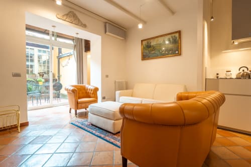 Luxury living room in Casa Verde apartment, Trastevere Roma, with cognac leather sofas, cream furnishings, and garden view
